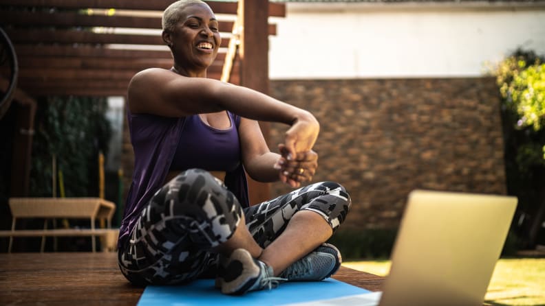 Woman doing a virtual exercise class, stretching her arms