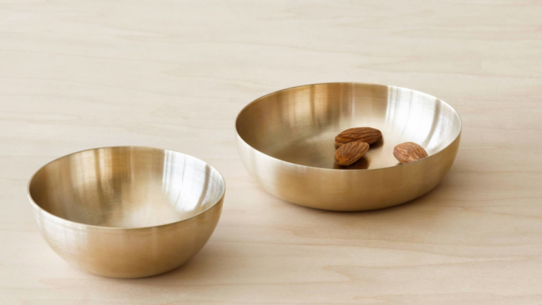 Two Kansa bronze dip bowls on a wooden counter