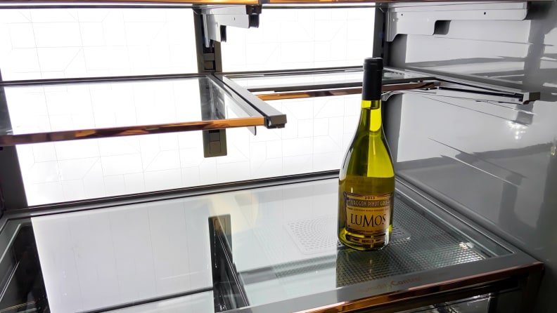 A shot of the interior of the Café CVE28DM5NBS5 French door refrigerator, with its flexible shelf slid back to allow a tall bottle of white wine to fit.