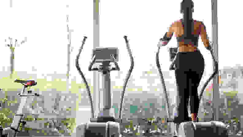 A woman using an elliptical machine looking out the window.