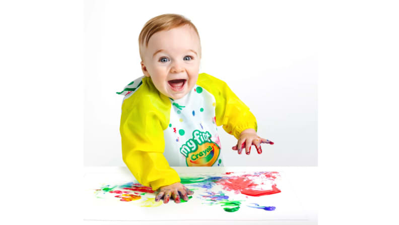 A toddler plays gleefully with finger paints.