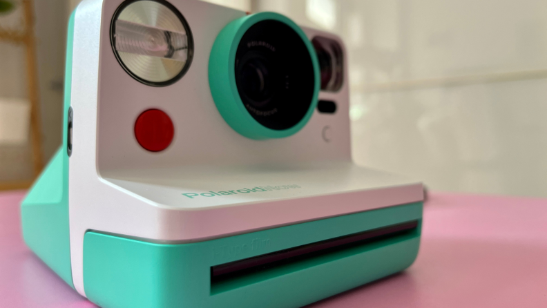 Front of white and teal polaroid camera.