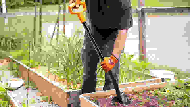 A person using a shovel in a garden bed
