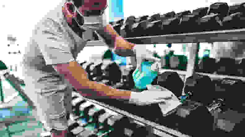 A man cleaning dumbbells at the gym.