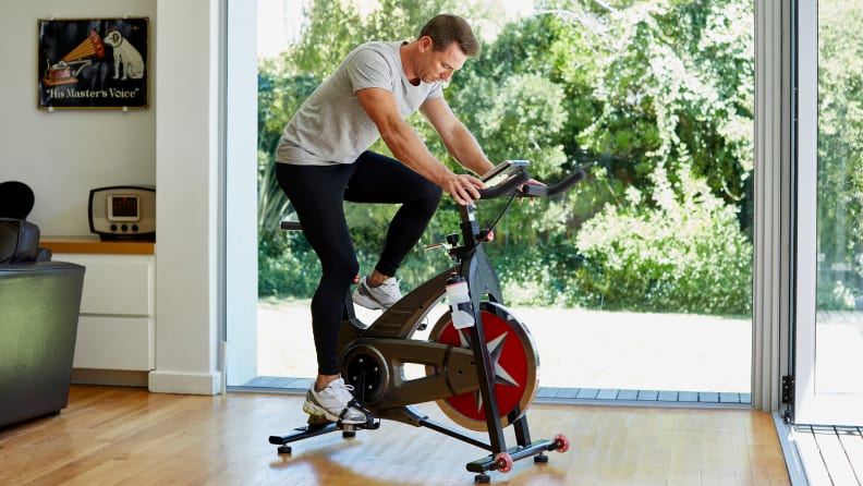 Full length of man working out on exercise bike at home