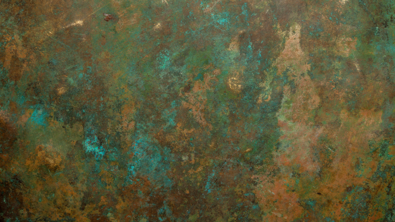 A detail of an oxidized copper vessel with shades of green and brown.