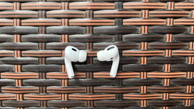 Two white AirPods Pro earbuds face each other on a braided bar.