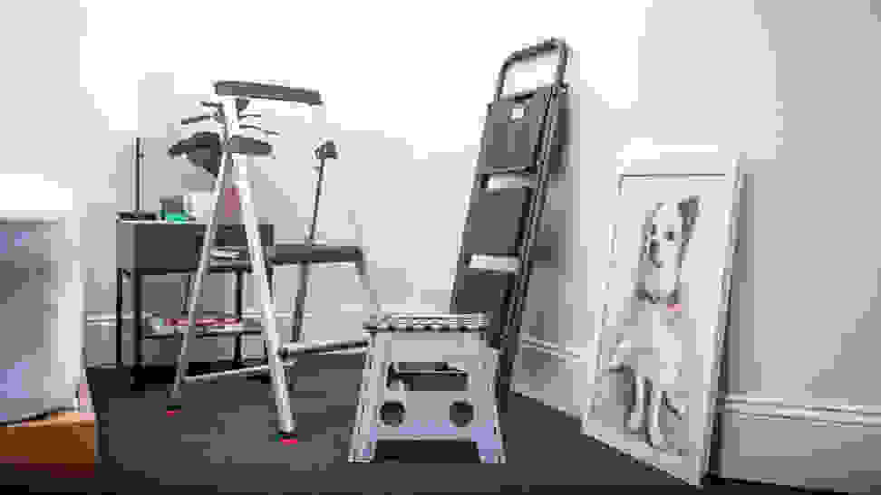 A grouping of three step stools stand in an office next to a portrait of a dog