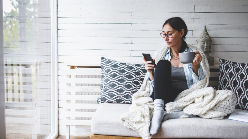 Woman on her phone under a blanket