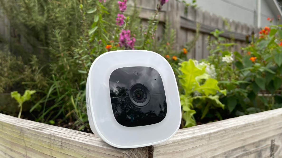 The Eufy SoloCam L20 sits on the edge of a garden bed.