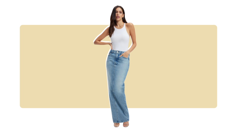 A model wearing a floor-length blue denim skirt and a white tank top.