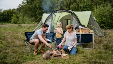 Family grills in front of a tent.