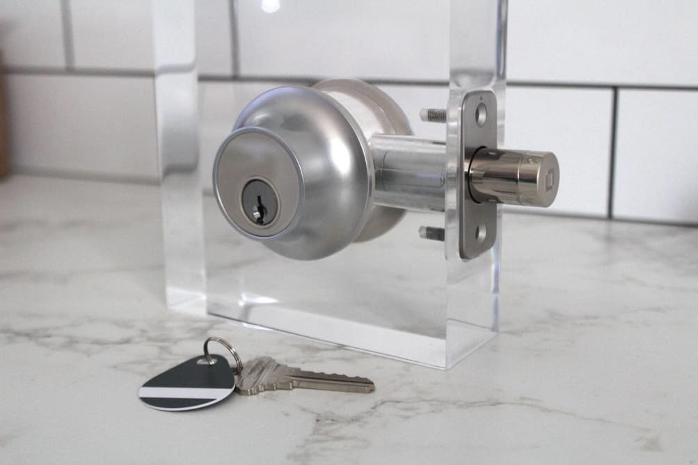 The Level Lock Plus Connect smart deadbolt set up on a test stand with a key and fob on the counter