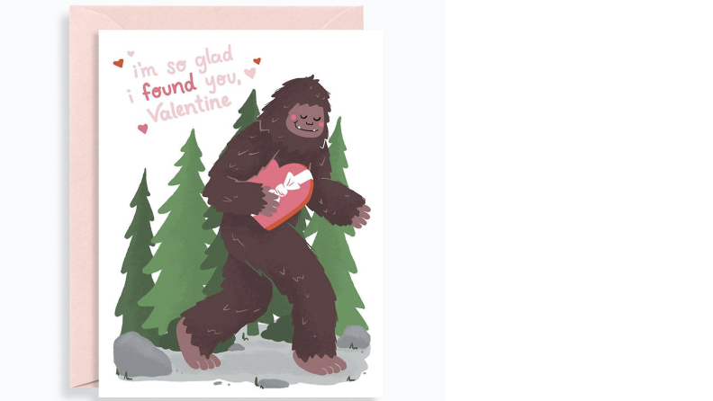 A greeting-card illustration: Bigfoot, a.k.a. Sasquatch, carries a heart-shaped box (presumably full of chocolates). "I'm so glad I found you, Valentine," the card reads.