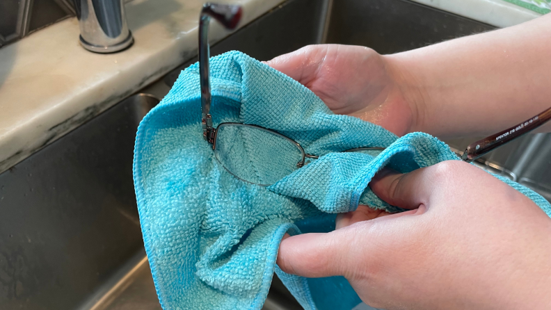Author cleaning glasses with blue microfiber cloth over sink