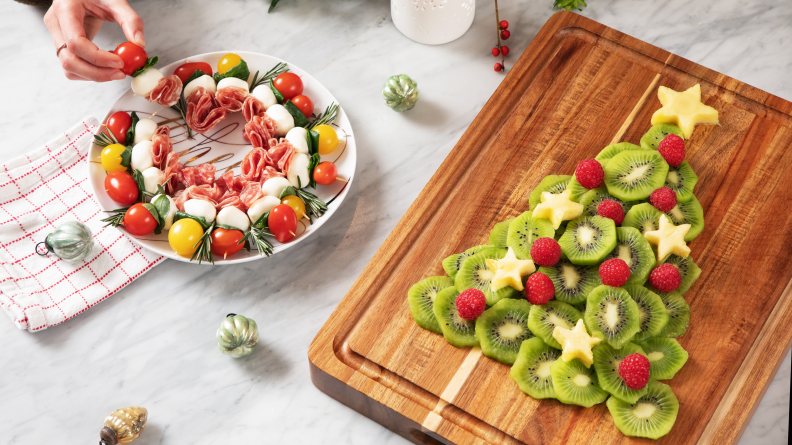 Wreath-shaped cheese board and fruit arranged in a Christmas tree on a countertop surface