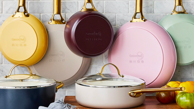 An assortment of colorful ceramic pans hang on a wall and sit on a counter in a kitchen.