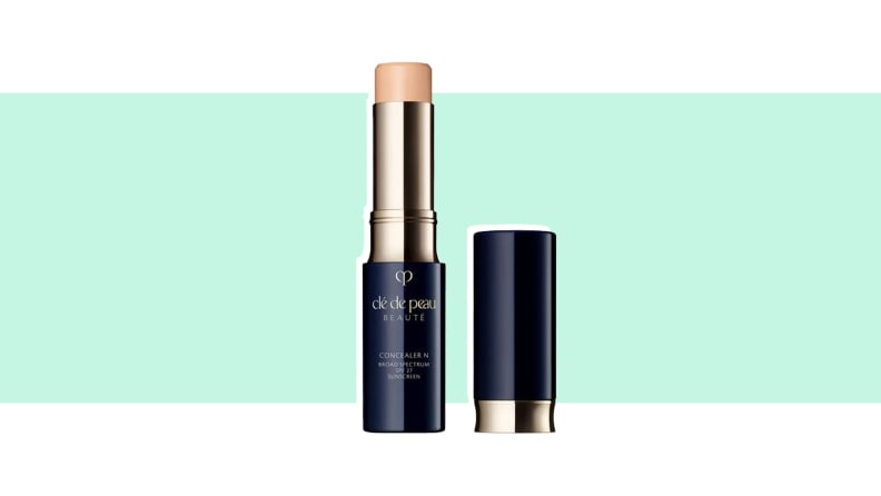 A tube of concealer against a green background.