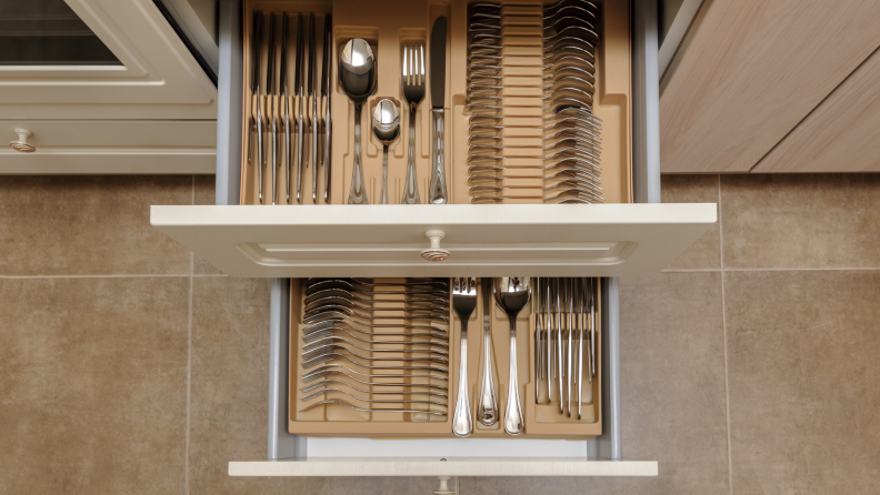 An opened kitchen drawer with silverware sets, viewed from above.