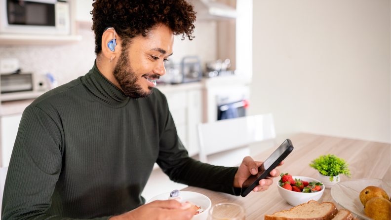 man sitting in kitchen eating while wearing hearing aids