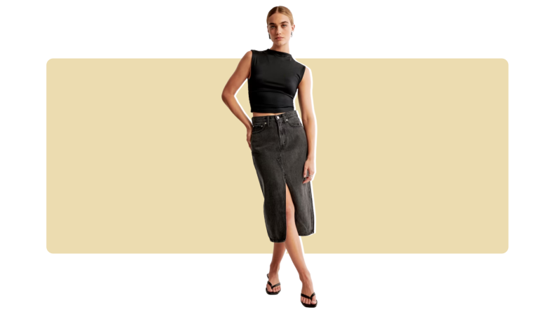 A model wearing a black midi-length denim skirt with a black tank top.