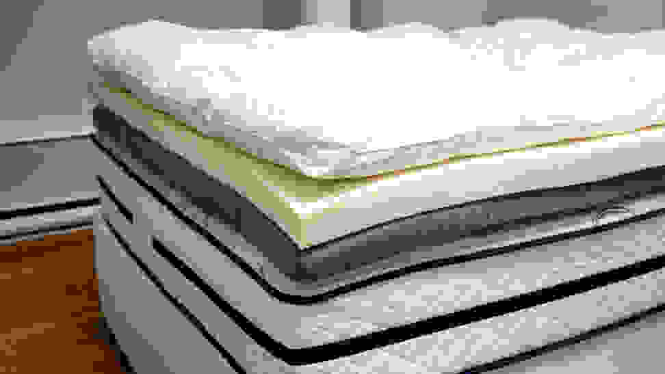 Close-up photo of a foam mattress topper and other layers of bedding.