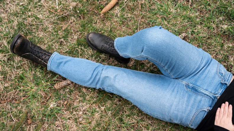 Girl wearing American Eagle jeans lies on the grass.