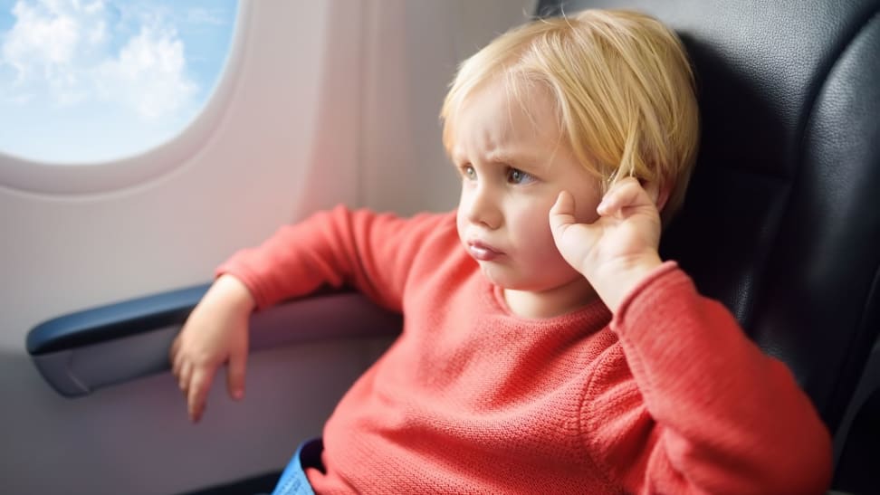 A pouting child sits on an airplane.