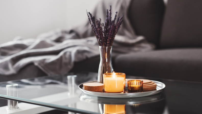 Closeup of a coffee table with a tray including a candle and lavender.