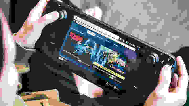 A close up of a handheld gaming console being held by adult human hands