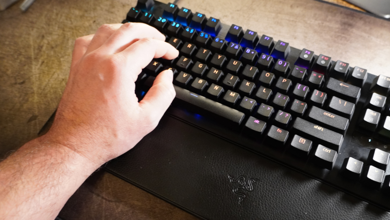 A hand with the wrist placed on the keyboard's hand rest.