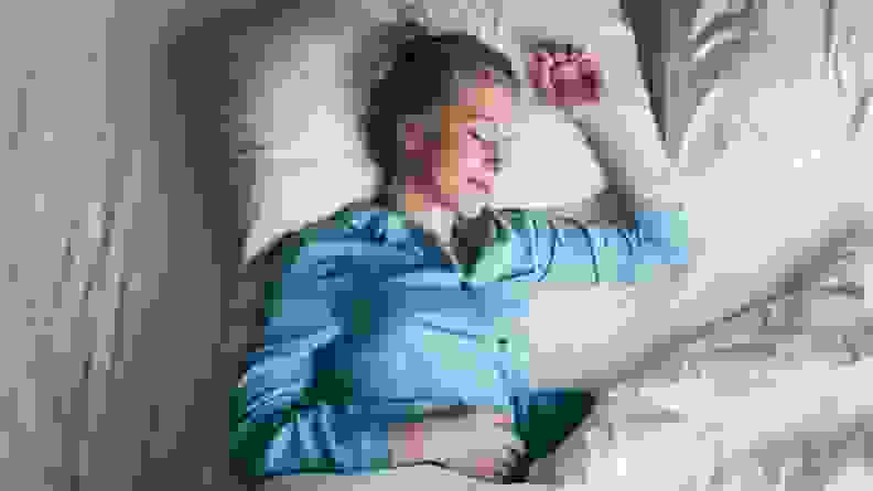 a woman sleeps happily in blue pajamas on white sheets