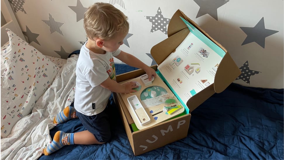 A young boy opens a cardboard box in bed