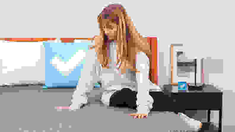 A person sitting on the Tuft & Needle Mint hybrid mattress.