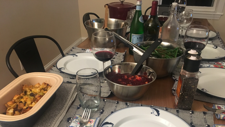 Stuffing, green beans, cranberry sauce and red wine on table