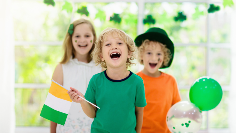 Family celebrating St. Patrick's Day. Irish holiday, culture and tradition. Kids wear green leprechaun hat and beard with Ireland flag and clover leaf. Children having fun at St Patrick party.