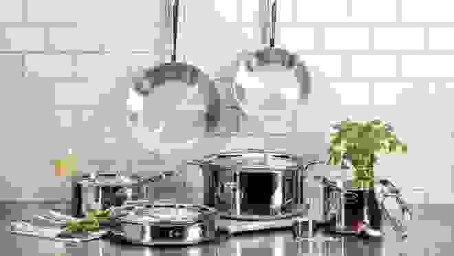 Stainless-steel pots and pans set on granite kitchen countertop.