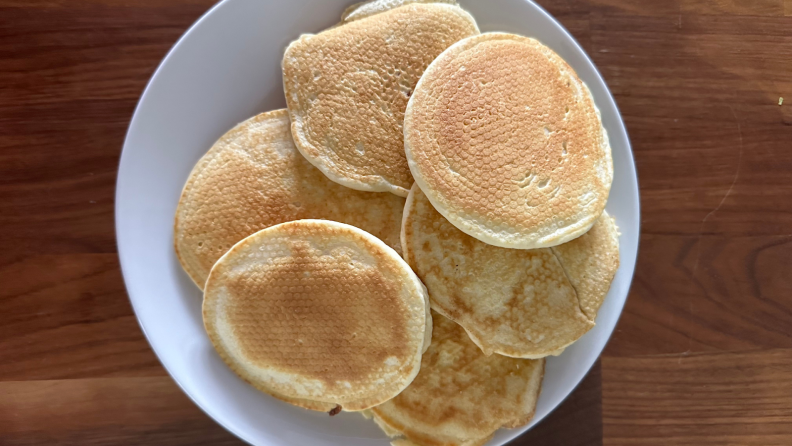 Pile of pancakes on plate with patterned design on each one.