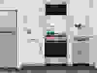 A small kitchen with a refrigerator, an oven range, utensils on the countertop, and so on.