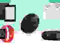 黑色Kindle平板电脑，红色苹果智能手表，黑色Eufy机器人真空吸尘器，黑色JBL蓝牙扬声器，绿色背景前的苹果Airpods。
