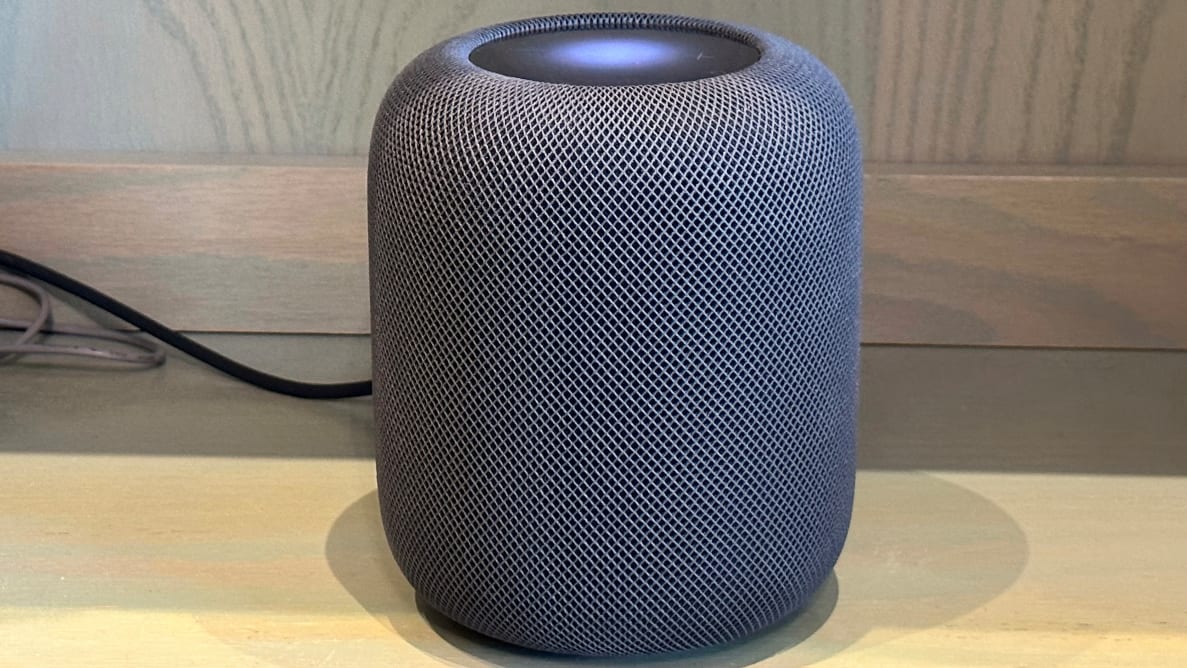 The second generation Apple HomePod sits on a wooden desk.