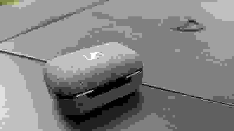 The grey fabric Sennheiser Momentum True Wireless 3 case sits on a black table.
