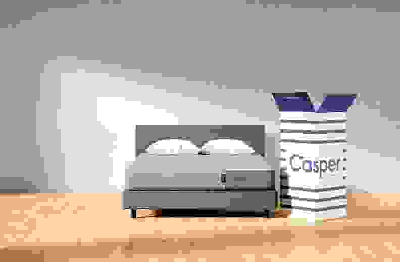 The Casper mattress set up in a complete bedding set with the Casper box next to it.