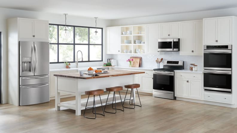 An open, white kitchen with the stainless steel Frigidaire Gallery FG4H2272UF at left.