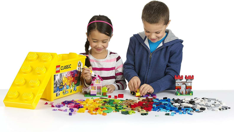 Two children playing with Lego blocks together at table.