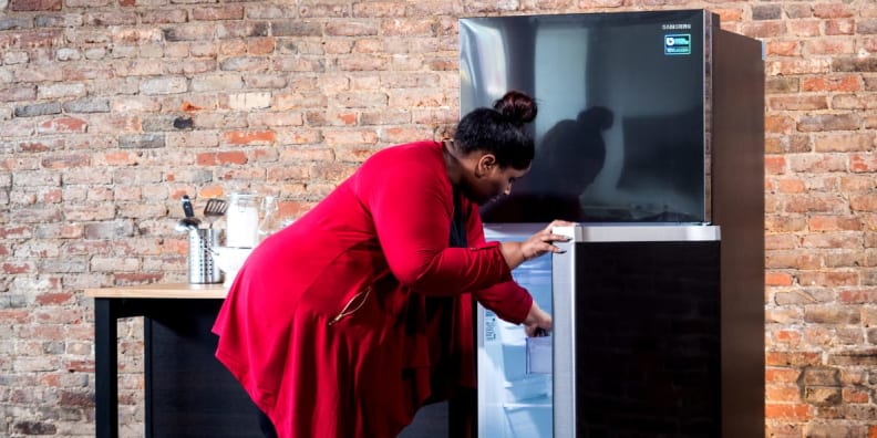 A woman in a red sweater looks into a refrigerator
