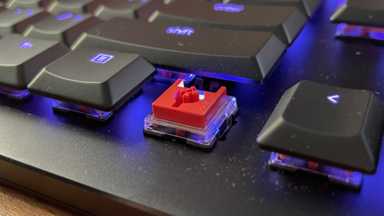 A removed key from a mechanical gaming keyboard shows the red switch system.