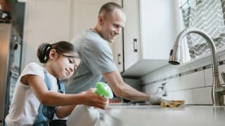 A man and young woman cleaning a sink
