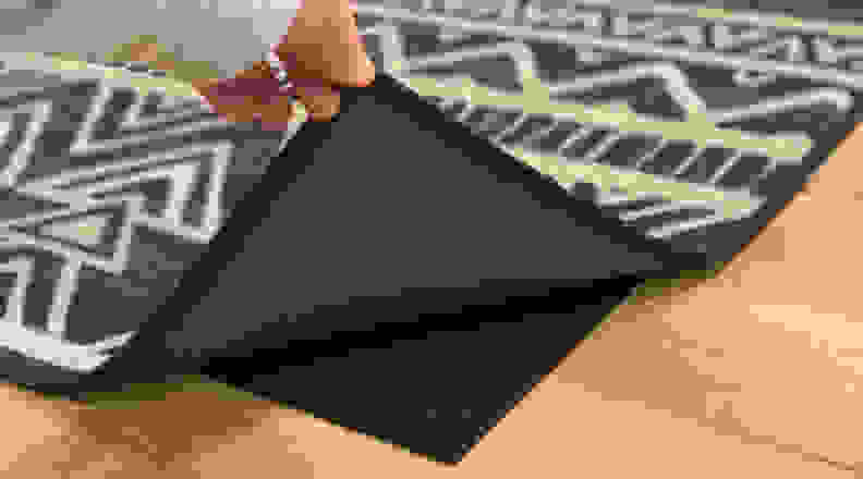 A person lifting up the Ruggable cover to expose the Ruggable rug pad.