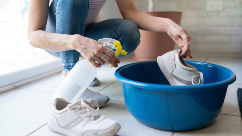 Disinfecting white sneakers in a bowl and using a detergent spray.
